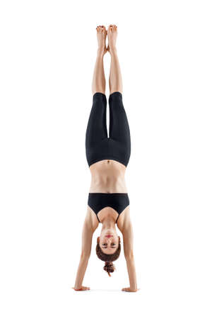 Young sporty woman doing headstand yoga asana pose isolated on white background. Adho Mukha Vrksasanaの写真素材