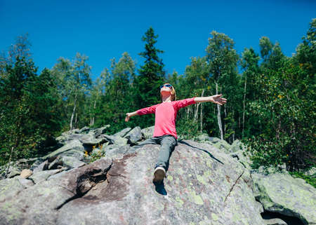 Happy little girl in the mountain with hands raised to the sun.の写真素材