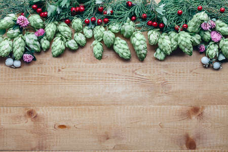 Flowers frame of hop twig, clover and red berries on wooden background with copy spaceの写真素材