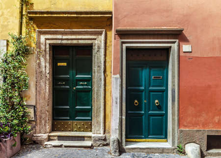 Two classic Italian doors on walls painted blue and orange in Romeの写真素材