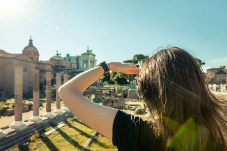 Woman looking forward with hand on forehead to archeological ruins in Rome. Back viewの写真素材