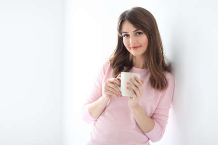 Young beautiful woman with cup of coffee on white background. Copy spaceの写真素材