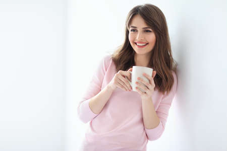 Laughing beautiful woman with cup of coffee on white background. Copy spaceの写真素材