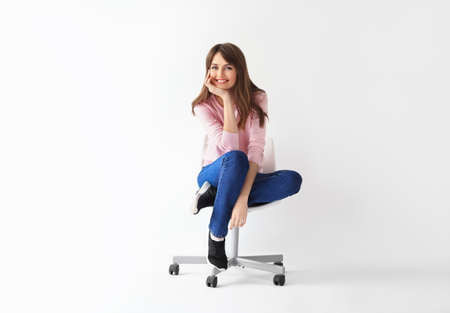 Beautiful smiling woman sitting on chair with copy space on white backgroundの写真素材