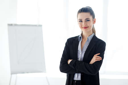 Portrait of young beautiful business woman in the office. Crossed armsの写真素材