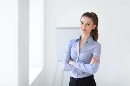 Portrait of young beautiful business woman in the office. Crossed armsの写真素材