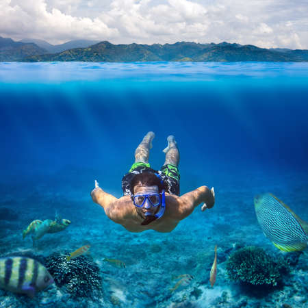 Underwater shoot of a young man snorkeling in a tropical sea on vacation. Design templateの写真素材
