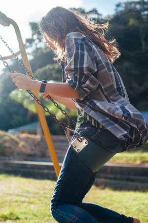 Side view of young happy girl on swing in sun light. Freedom woman