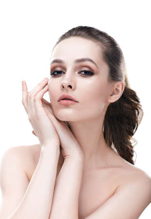 Beautiful young woman with clean healthy skin touch her face isolated on white background. Cosmetologyの写真素材