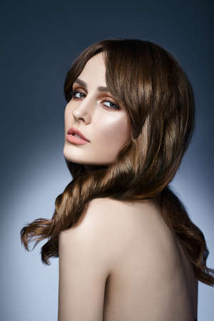 Beauty portrait of young pretty woman with long hair on dark backgroundの写真素材