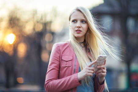 Portrait of beautiful young woman using her mobile phone in the streetの写真素材