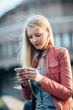 Portrait of beautiful young woman using her mobile phone in the streetの写真素材