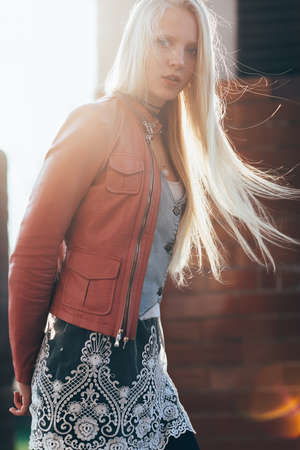 Young beautiful blond woman portrait with wind in her hair backlit by sunshineの写真素材
