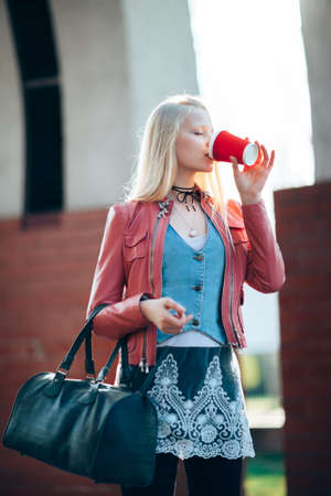 Beautiful blond woman drinking coffee in city streetの写真素材