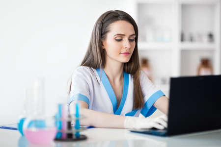 Portrait of confident female scientist working on laptop in chemical laboratoryの写真素材