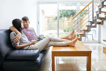 Happy attractive couple talking sitting on the couch in modern home. Family conceptの写真素材