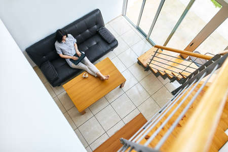 Pretty young woman working on laptop at modern cozy home. Top viewの写真素材