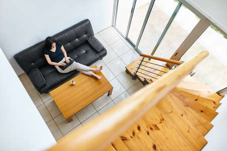 Pretty young woman working on laptop at modern cozy home. Top viewの写真素材