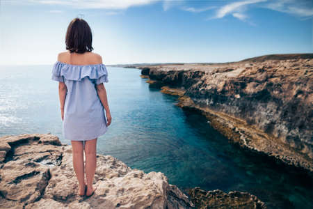 Young woman enjoying beautiful sea view on Greco cape in Cyprus. Back viewの写真素材