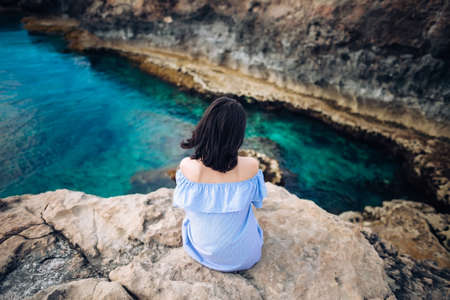 Young woman enjoying beautiful sea view on Greco cape in Cyprus. Back viewの写真素材