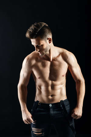Portrait of a sexy muscular shirtless man posing against dark backgroundの写真素材