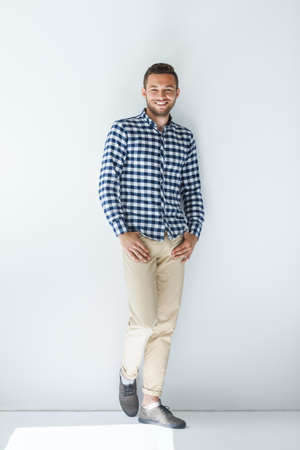 Full length portrait of handsome stylish man in casual clothes posing and leaning at white wallの写真素材