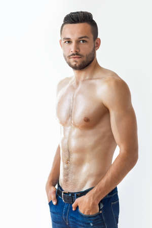 Portrait of a sexy muscular shirtless man against white wallの写真素材