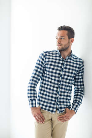 Handsome sexy man in stylish casual clothes leaning at white wallの写真素材