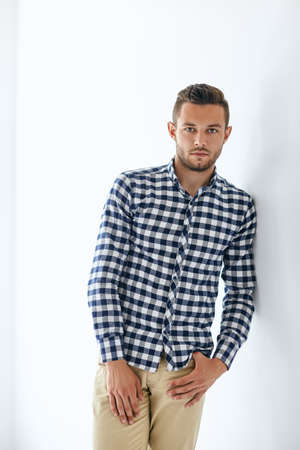 Handsome sexy man in stylish casual clothes leaning at white wallの写真素材