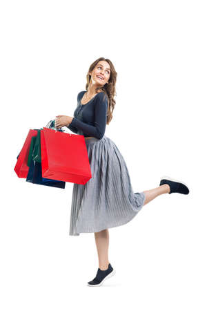 Happy running beautiful woman with many colorful shopping bags isolated on white background. Full length portraitの写真素材