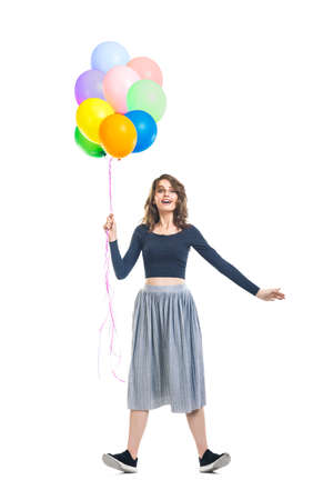 Surprised beautiful woman holding colorful balloons and having fun isolated on white background. Full length portraitの写真素材
