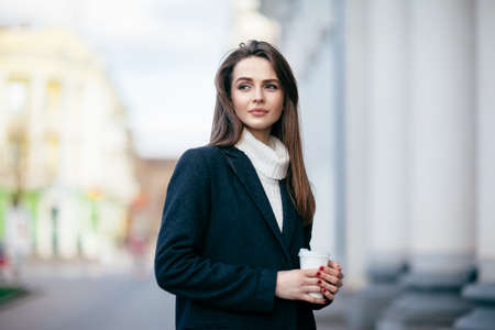 Young beautiful woman with cup of coffee in city street. Urban lifeの写真素材