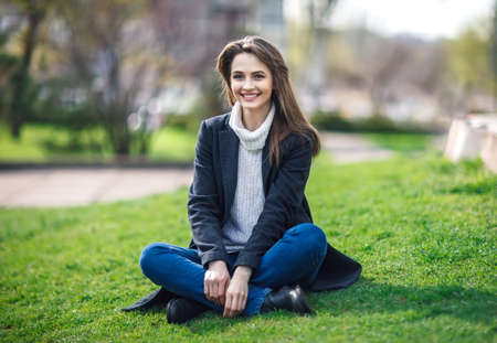 Beautiful smiling woman sitting on a grass outdoor. relax concept
の写真素材