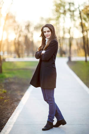 Full length portrait of young beautiful woman in park on sunsetの写真素材
