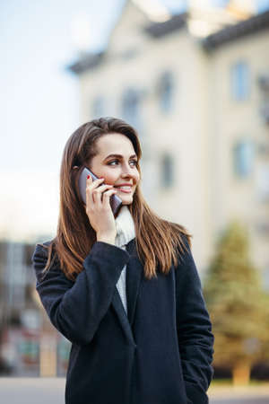 Happy beautiful woman speaking on mobile phone on the city streetの写真素材