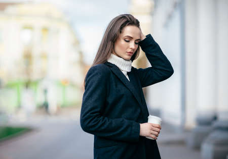 Young beautiful woman with cup of coffee in city streetの写真素材