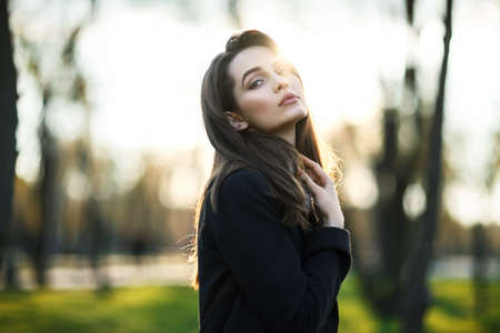 Young beautiful woman portrait in sun light on sunset time in city parkの写真素材