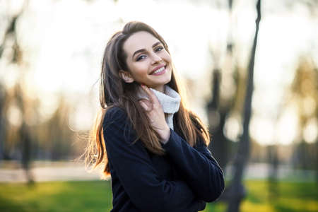 Smiling beautiful woman portrait in sun light on sunset time in city parkの写真素材