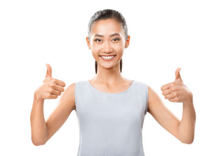 Half body photo of cheer Asian girl giving thumb up. Happy woman with arms bent at the elbows and thumbs up fun sign isolated on white background. Positive, successful, approve, motivation gestureの写真素材