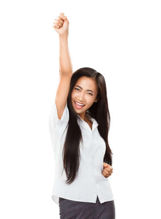 Asian young woman rejoices at her success or victory. Casual businesswoman cheering winning with arm up, smiling and looking at camera. Image isolated on white backgroundの写真素材