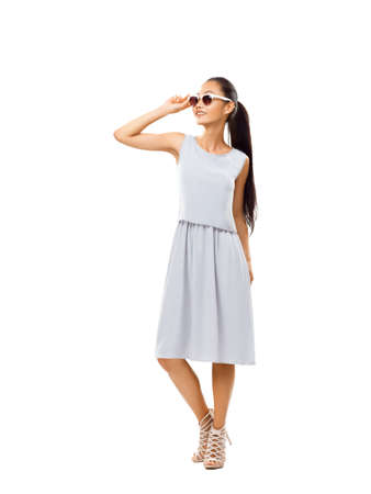 Studio portrait of full-length Asian beautiful woman with sunglasses. Young girl in casual style enjoying life. Happy model smiling and looking up isolated on white background. Summer concept image of successful carefree femaleの写真素材