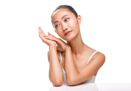 Beauty portrait of cute Asian woman with dreaming face. Young model smiling and looking to the side. Spa, clean skin, beauty treatments concept photo isolated on white backgroundの写真素材