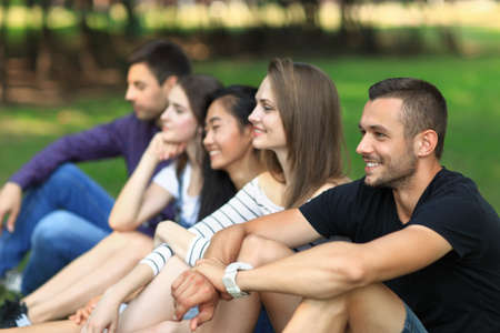 Adult attractive friends having fun on open air. Focus on handsome man smiling and looking at...