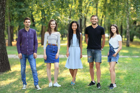 Happy smiling student friends women and men standing together outdoors. Portrait in full growth of five young confident people on green forest background. Team, friendship, unity conceptの写真素材