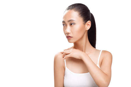 Beauty portrait of cute Asian woman with dreaming face. Young model smiling and looking to the side. Spa, clean skin, beauty treatments concept photo isolated on white backgroundの写真素材