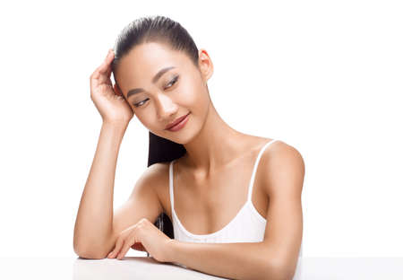 Beauty portrait of cute Asian woman with dreaming face. Young model smiling and looking to the side. Spa, clean skin, beauty treatments concept photo isolated on white backgroundの写真素材