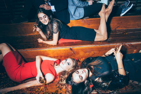 Beautiful young women having fun on a crazy party lying on the floor. New year, Birthday, Holiday Eventの写真素材