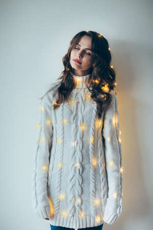 Festive dreaming woman portrait wrapped in Christmas lights. Holiday conceptの写真素材