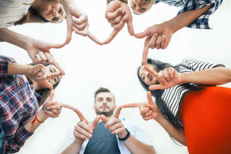 Five young smiling women and men make star shape from fingers. Happy friends or students show a sign...