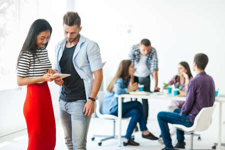 Businessman and businesswoman using tablet for working with their team on background in the office